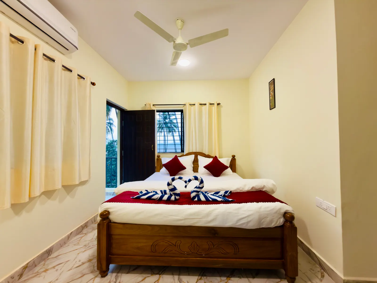 Deluxe Double Room with Kitchen: double bed with towel swans, air conditioner and balcony door